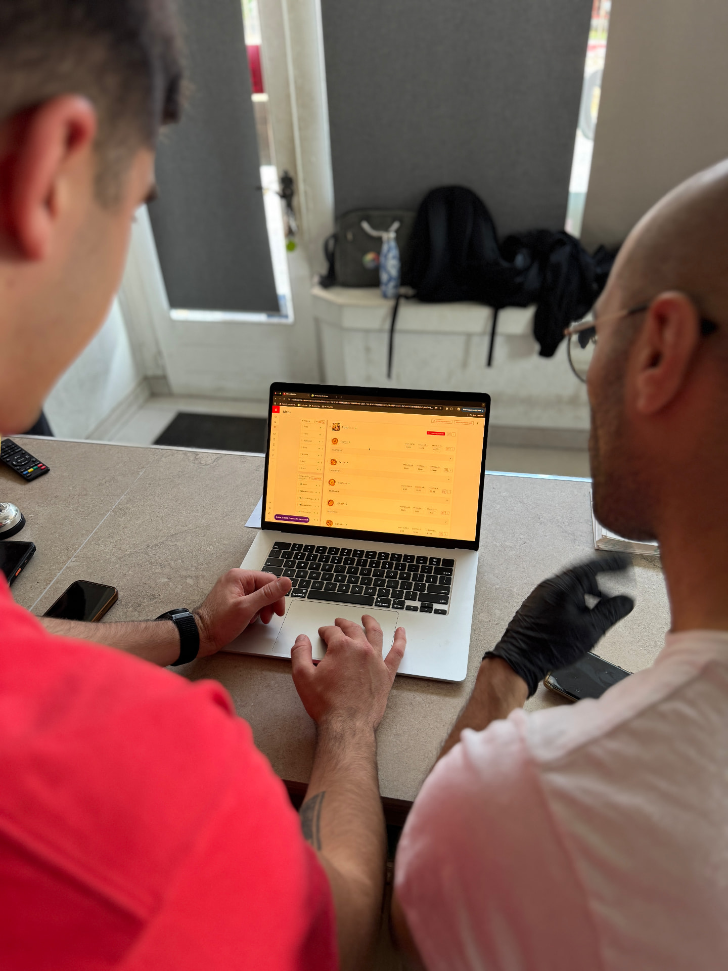Consulente EatLive configura il menu sul portatile insieme al ristoratore, al bancone del locale